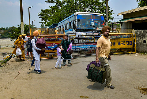 People move through a barricade at the Dehradun-Himachal border as security tightness, after a tense face-off between a large group of Nihang Sikhs and security personnel at the Kulhal border check post near Paonta Sahib of Sirmaur district on late Thursday, in Dehradun, Uttarakhand.