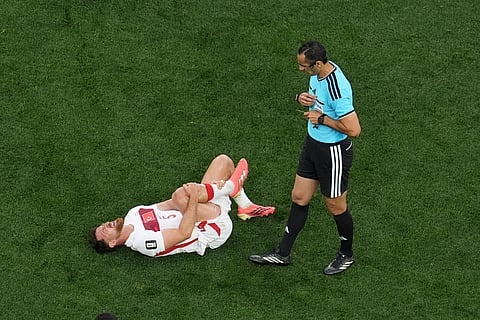 Turkey's Salih Ozcan (5) holds his left leg in front of referee Mustapha Ghorbal during the first half of a World Cup Group D soccer match between Turkey and the United States in Inglewood, Calif., near Los Angeles, Thursday, June 25, 2026.