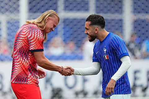 Norway's Erling Haaland and France's Rayan Cherki, right, greet each other as they meet on the pitch for the warmup before the World Cup Group I soccer match