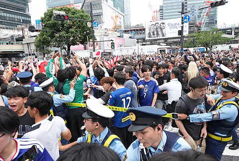 Police officers try to move fans out of Tokyo's Shibuya Crossing, as the fans react after a World Cup Group F soccer match in the United States between Japan and Sweden. 
