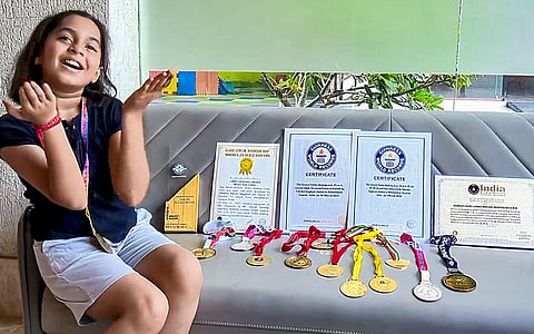 Eight-year-old Takshvi Vaghani poses with her Guinness World Records certificates and medals after setting the world record for the lowest limbo skating by skating under a bar set at 16 cm (6.29 inches), in Ahmedabad.