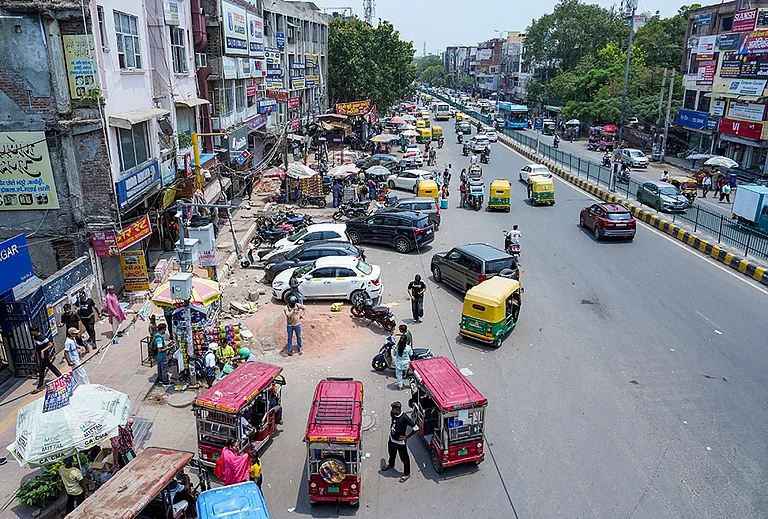 Vehicles, roadside vendors and commercial encroachments occupy a footpath, forcing pedestrians to use the carriageway, at Laxmi Nagar, in New Delhi. The Supreme Court has held that the right to walk on a demarcated footpath is a fundamental right. - | Photo: PTI/Arun Sharma