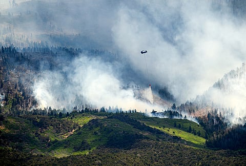 A helicopter drops water on the Cottonwood Fire burning near Beaver, Utah.