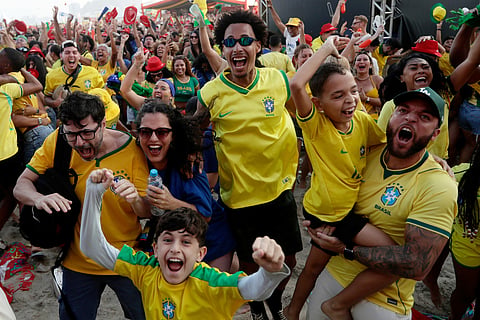 Brazil fans celebrate after Brazil scored its second goal against Japan at the World Cup soccer match as they watch a live broadcast on Copacabana beach in Rio de Janeiro