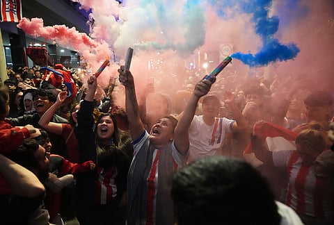 A fan holds a flare during a gathering to watch the World Cup round of 32 soccer match between Paraguay and Germany in Asuncion, Paraguay.