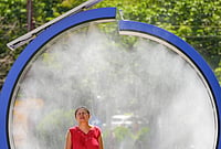 Early Heat Wave Sweeps Europe – In Photos | Photo: AP/Vadim Ghirda : A woman cools off in a water mist machine installed by city administration to assist people in coping with the heat on a torrid day, as the National Weather forecaster issued an extreme heat code red warning for most parts of the country, in Bucharest, Romania, Monday, June 29, 2026.