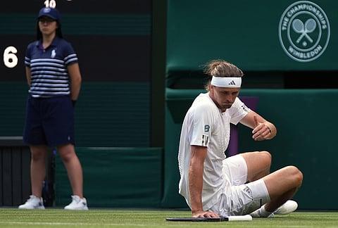 Alexander Zverev of Germany falls during his match against Alexander Blockx of Belgium in the first round men's singles match of the Wimbledon Tennis Championships in London, Tuesday, June 30, 2026. 