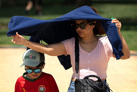 Visitors use a jacket for shade as they walk at the Great American State Fair on the National Mall in Washington. 
