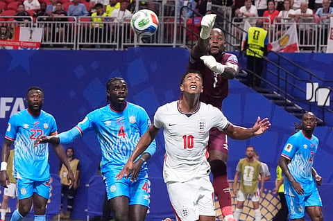 Congo goalkeeper Lionel Mpasi makes a save over England's Jude Bellingham during a World Cup round of 32 soccer match in Atlanta