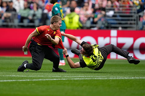 A pitch invader is held by security during the World Cup round of 32 soccer match between Belgium and Senegal in Seattle