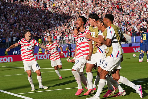 United States' Malik Tillman (17) celebrates with teammates after scoring on a free kick during the World Cup round of 32 soccer match between the United States and Bosnia in Santa Clara, California, near San Francisco.
