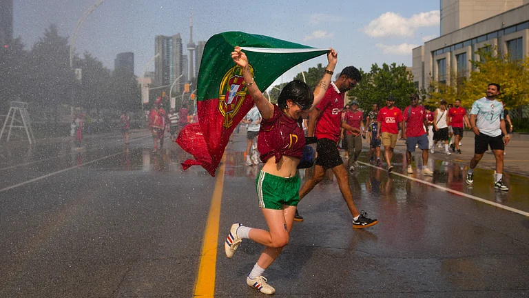A Portugal fan runs through a water jet, as fans try to cool off ahead of a FIFA 2026 World Cup round of 32 match between Portugal and Croatia in Toronto on Thursday, July 2, 2026. - (Chris Young/The Canadian Press via AP)