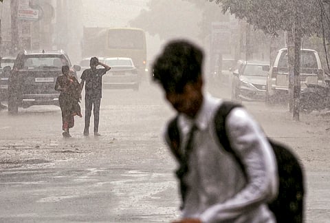 People walk on a road amid rain, in Patna.