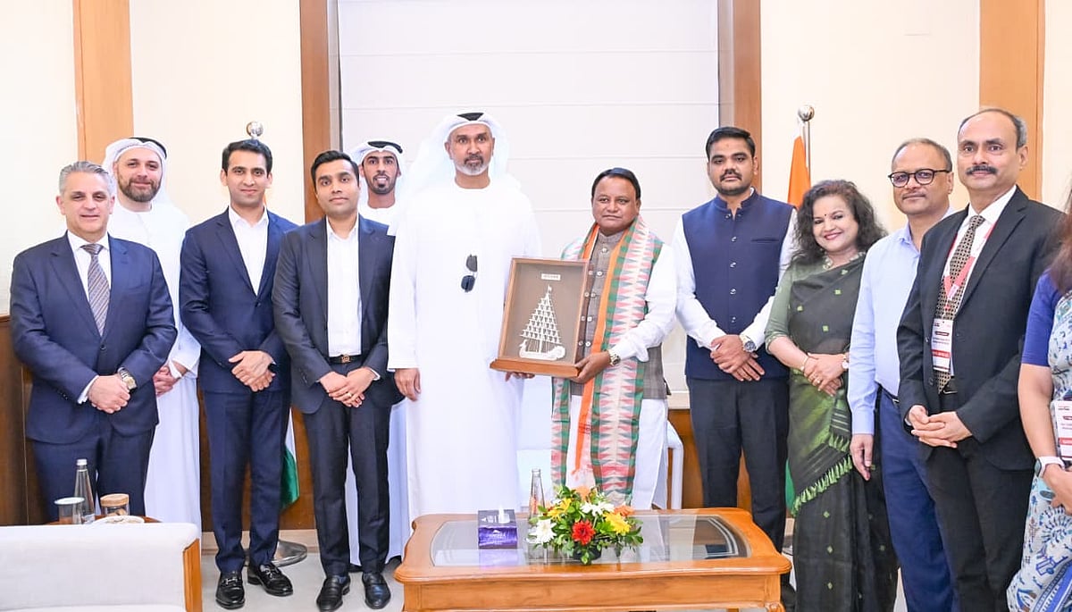 Indian and UAE officials smile while holding a framed artwork at the signing ceremony