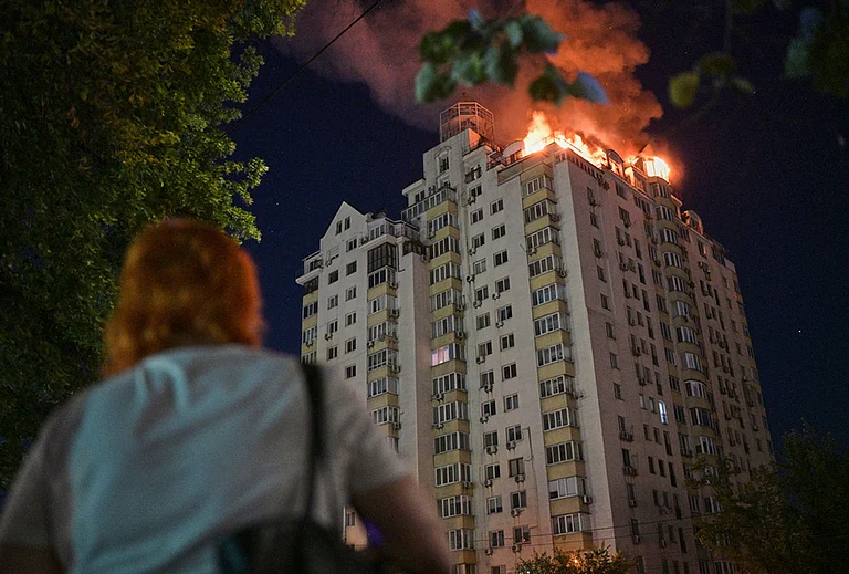 A woman looks at an apartment building burning after a Russian missile attack in Kyiv, Ukraine. - | Photo: AP/Danylo Antoniuk