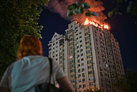 | Photo: AP/Danylo Antoniuk : A woman looks at an apartment building burning after a Russian missile attack in Kyiv, Ukraine.