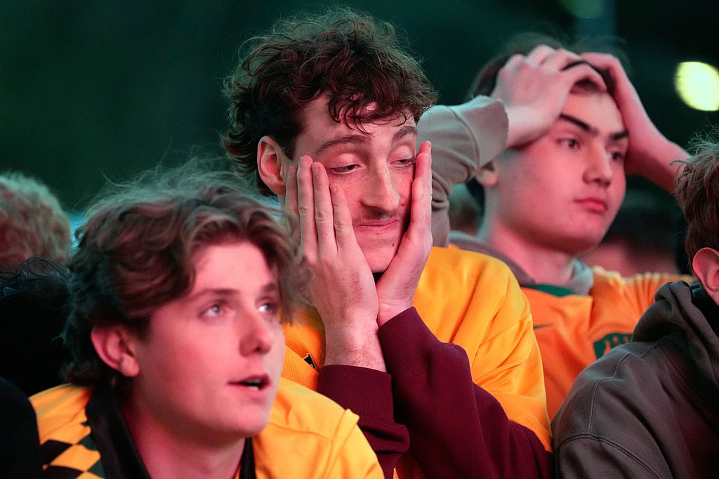 Dejected fans react after watching large screens in a park in Sydney
