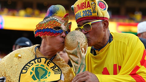 Fans kiss a replica trophy before the World Cup round of 32 soccer match between Colombia and Ghana in Kansas City, Mo., Friday, July 3, 2026.