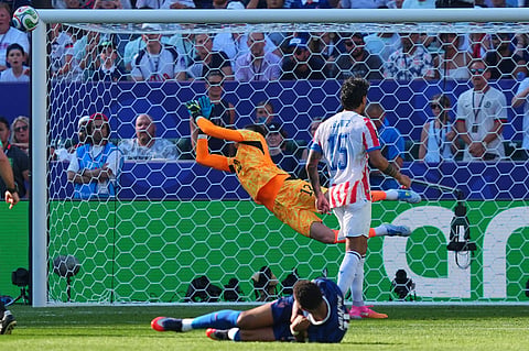 France's Kylian Mbappe (10) tries a shot as Paraguay goalkeeper Orlando Gill (12) dives for the ball during the World Cup round of 16 soccer match between Paraguay and France in Philadelphia