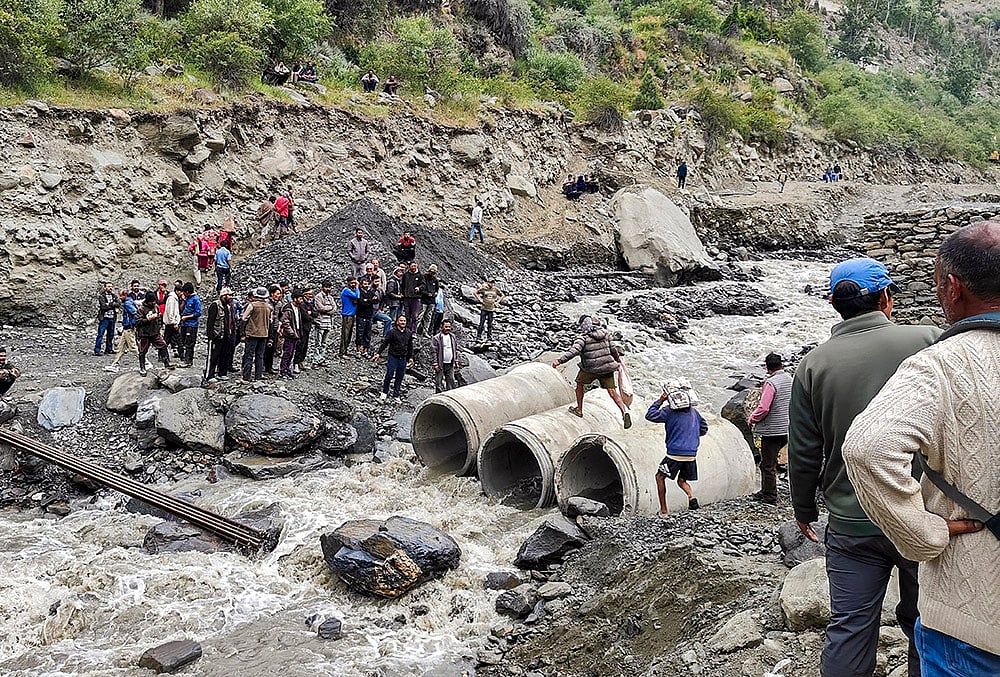 People cross a stream over concrete culvert pipes