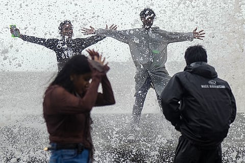 People stroll amid high tide at Marine Drive, in Mumbai.