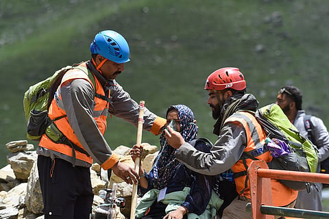 Jammu and Kashmir Police's Mountain Rescue Team (MRT) officials assist an Amarnath pilgrim during the annual pilgrimage at Pahalgam, in Anantnag district, Jammu and Kashmir.