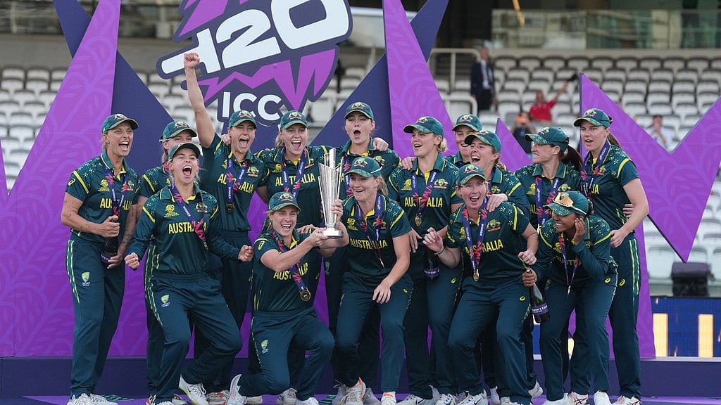 Alastair Grant/AP Photo : The Australia team celebrate on the podium with the trophy after winning the Women's T20 Cricket World Cup final between England and Australia in London