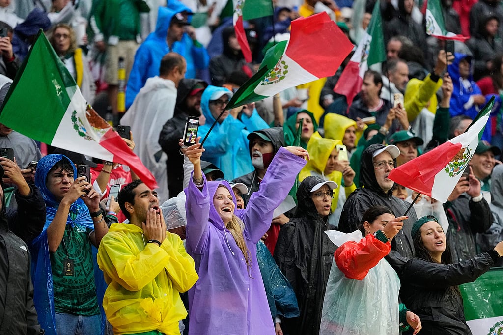 Fans react as they wait for the start of the World Cup round of 16 soccer match between Mexico and England that is delayed due to bad weather in Mexico City