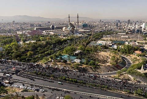 Mourners pray on a road adjacent to the Imam Khomeini Mosalla Grand Mosque, top, during funeral ceremonies for the slain Iranian Supreme Leader Ayatollah Ali Khamenei and members of his family in Tehran, Iran, Sunday, July 5, 2026. 