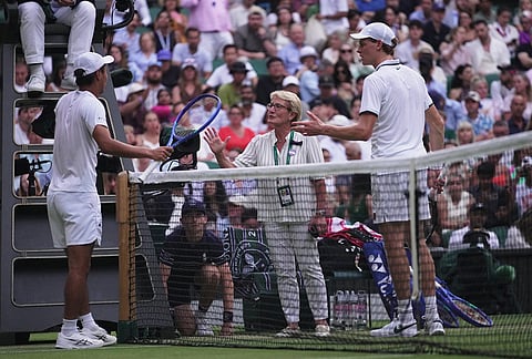 Shintaro Mochizuki of Japan, left, and Jannik Sinner of Italy, right, are told to pause their match in order to close the roof, in the fourth round men's singles competition at the Wimbledon Tennis Championships in London, Sunday, July 5, 2026.