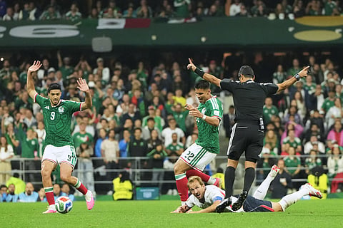 Referee Alireza Faghani, top right, gestures as England's Harry Kane, bottom, goes down while challenging Mexico's Guillermo Martinez (22) and Raul Jimenez (9) during the World Cup round of 16 soccer match between Mexico and England in Mexico City, Sunday, July 5, 2026