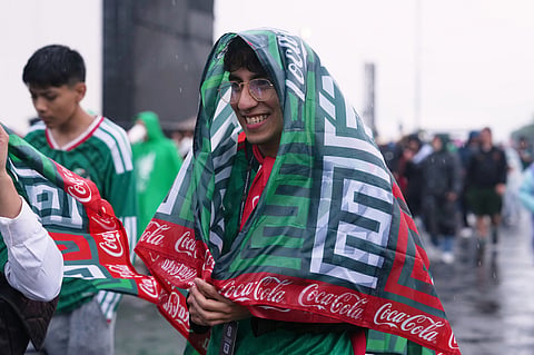 A Mexico supporter covers itself from the rain prior to the World Cup round of 16 soccer match between Mexico and England in Mexico City,