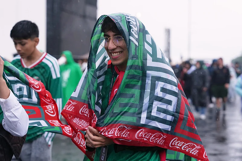 A Mexico supporter covers itself from the rain prior to the World Cup round of 16 soccer match between Mexico and England in Mexico City,