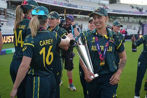 Australia's Ashleigh Gardner, carries the trophy as teammates celebrate after winning the Women's T20 Cricket World Cup final between England and Australia in London.