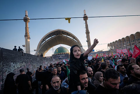 A little girl raises her fist from atop a man's shoulders as mourners gather during funeral ceremonies for slain Iranian Supreme Leader Ayatollah Ali Khamenei and members of his family at the Imam Khomeini Mosalla Grand Mosque in Tehran, Iran, Sunday, July 5, 2026. 