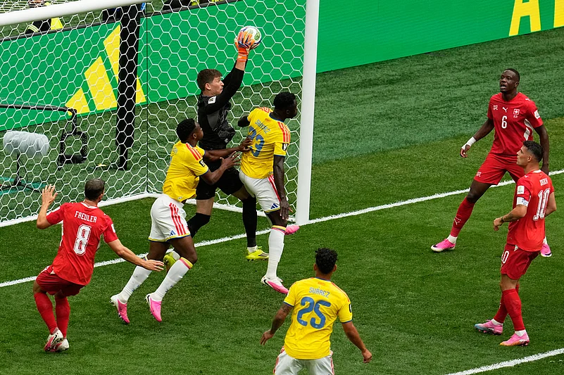 Switzerland goalkeeper Gregor Kobel makes a save over Colombias Davinson Sanchez (23) and Jhon Lucumi during the World Cup round of 16 soccer match in Vancouver, British Columbia