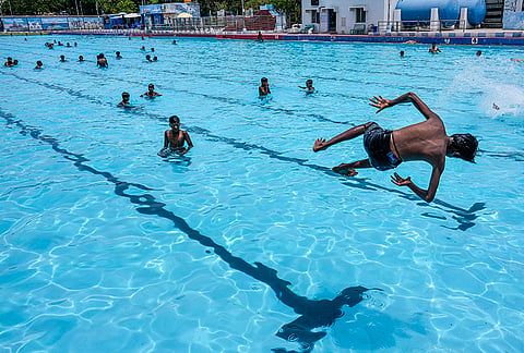 A young boy jumps into Marina Beach swimming pool to escape the heat on a hot summer day, in Chennai, Tamil Nadu.