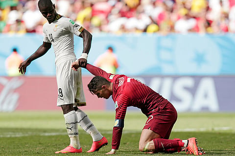 Ghana's Jonathan Mensah helps Portugal's Cristiano Ronaldo get up after he missed a chance to score during the group G World Cup soccer match in Brasilia, Brazil, June 26, 2014.
