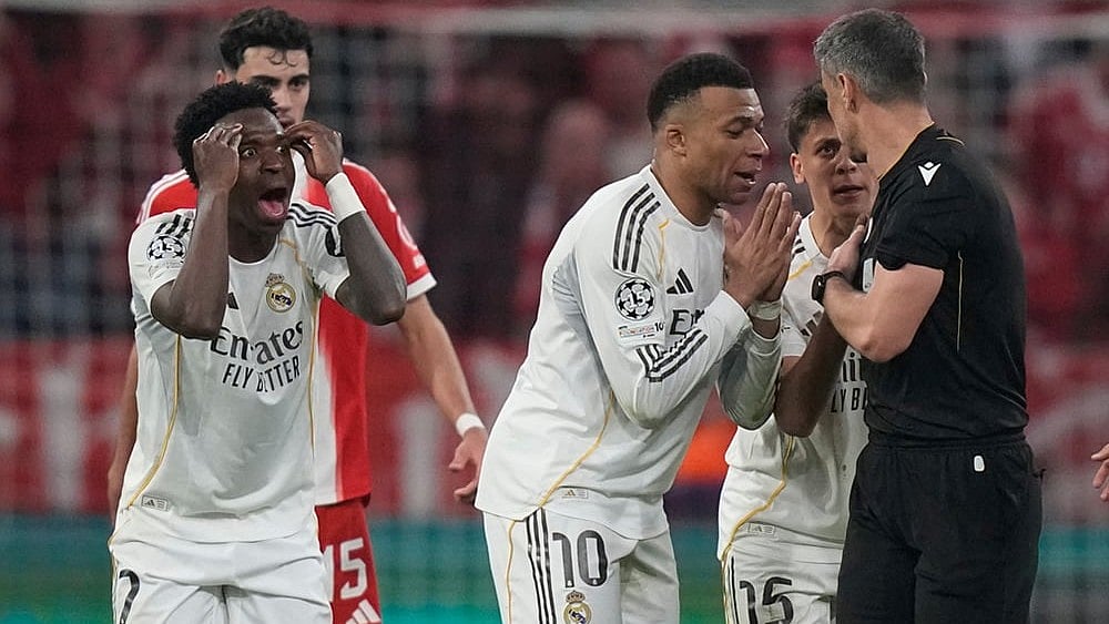 Real Madrid's Kylian Mbappe, center, and Vinicius Jr., left, disagree with referee Slavko Vincic during the Champions League quarterfinal second leg soccer match between Bayern Munich and Real Madrid in Munich, Germany. - | Photo: AP/Matthias Schrader