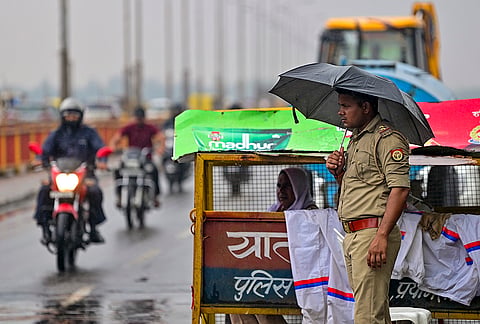 A police official stands guard amid rain, in Prayagraj, Uttar Pradesh.