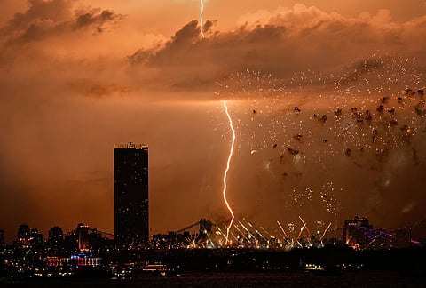 A bolt of lightning strikes as fireworks are set off of the Brooklyn Bridge, as seen from Bayonne, New Jersey.