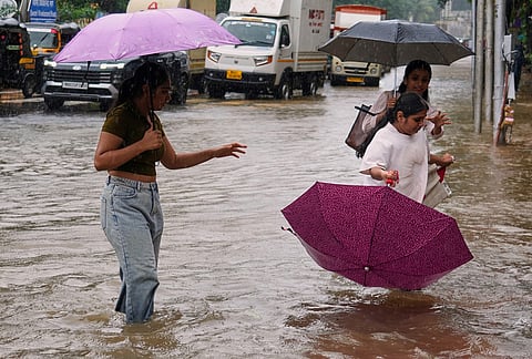 Girls walk through a water-logged street during monsoon rains in Mumbai, India, Saturday, July 4, 2026. 