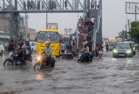 Commuters wade through a severely waterlogged road following heavy rainfall, in Gurugram, Haryana, Tuesday, July 7, 2026. 