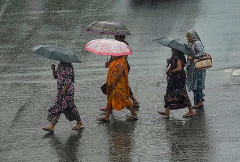 People make their way amid rainfall, in New Delhi. Rain lashed parts of the national capital on Wednesday, with the India Meteorological Department (IMD) issuing a 'yellow' alert for more showers and thunderstorms during the day. 