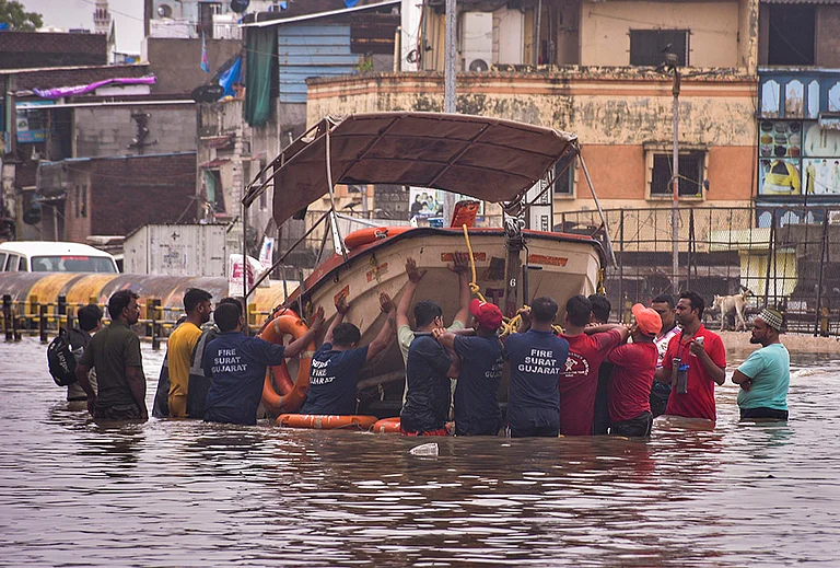 Fire and emergency services personnel deploy a rescue boat in the flood-affected Limbayat Mithi Khadi area following heavy monsoon rainfall, in Surat. Heavy rain inundated several parts of the city, prompting rescue and relief operations. - | Photo: PTI