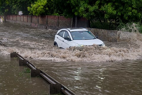 A vehicle wades through a severely waterlogged road following heavy rainfall, in Gurugram, Haryana, Tuesday, July 7, 2026. 