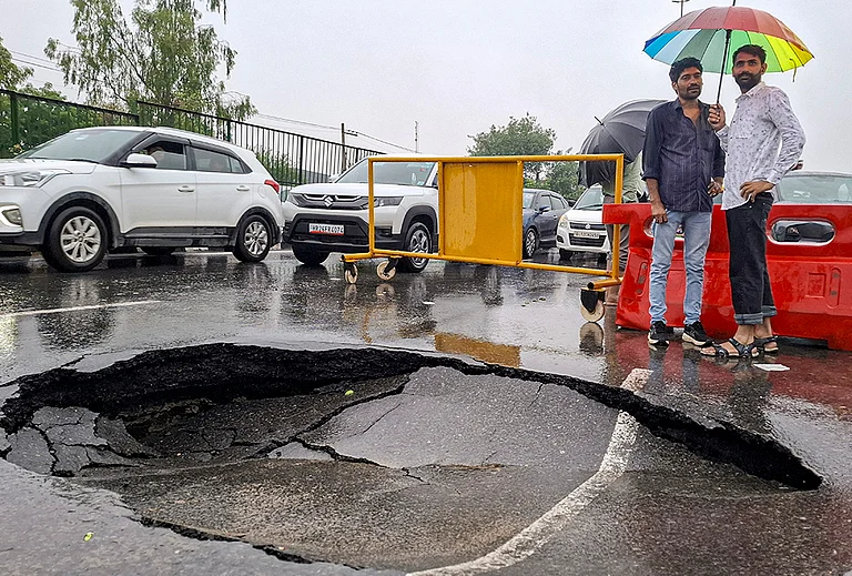 Vehicles move near a caved-in section of a road following monsoon rains, in Gurugram, Tuesday, July 7, 2026. - | Photo: PTI