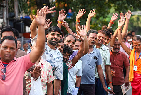 Pilgrims wave as they wait for registration for the annual Amarnath Yatra outside a registration centre, in Jammu.