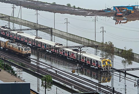 Trains run on waterlogged railway tracks after heavy rainfall, in Palghar, Maharashtra,  Wednesday, July 8, 2026. 