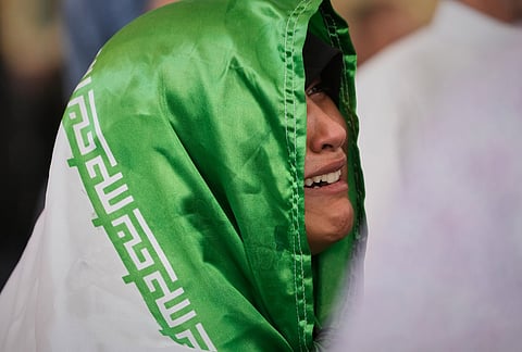 A mourner, draped in an Iranian flag, reacts during funeral prayers for the late Iranian Supreme Leader Ayatollah Ali Khamenei at the Imam Ali Shrine in Najaf, Iraq, Wednesday, July 8, 2026. 